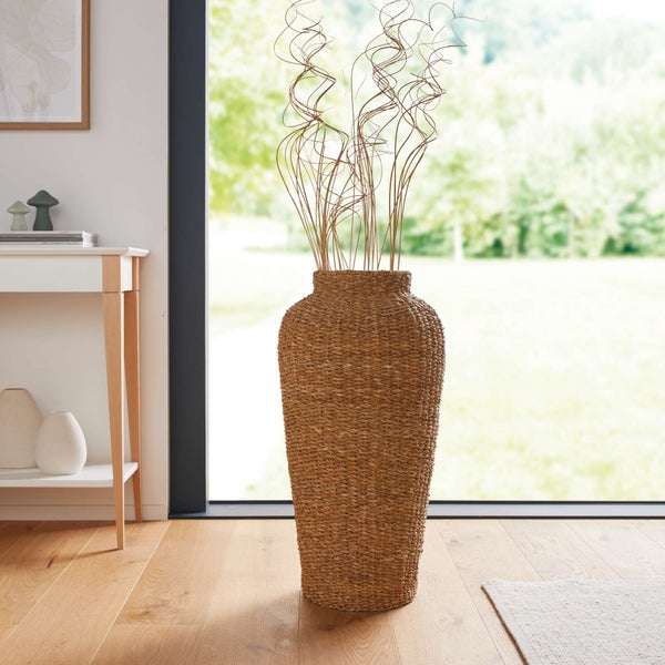 Dekorative Bodenvase aus Rattan mit Zweigen in einem hellen Wohnraum.