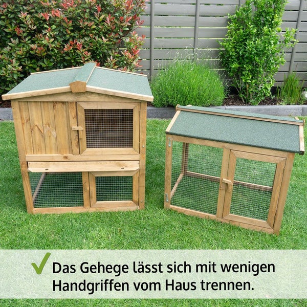 Zweistöckiger Kleintierstall aus Holz mit abnehmbarem Freilaufgehege auf einer Rasenfläche im Garten.