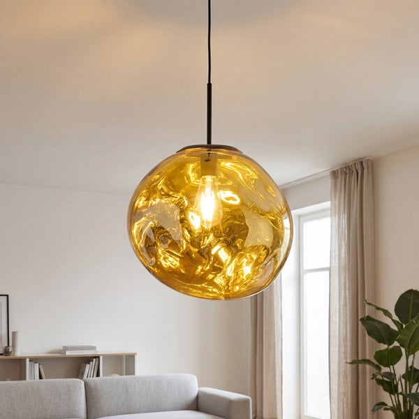 Moderne Pendelleuchte mit organisch geformtem Glasschirm in Gold-Optik, hängend in einem hellen Wohnzimmer über einem Sofa.
