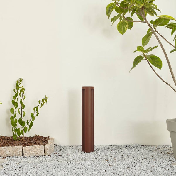 Moderne braune Pollerleuchte in einem minimalistischen Garten mit hellem Kies und einer Kletterpflanze.
