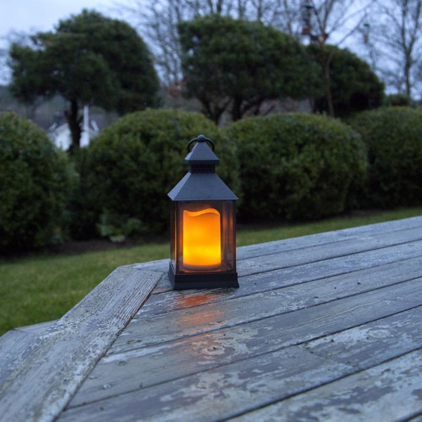 Dekorative Laterne mit LED Kerze auf einem Holztisch im Garten
