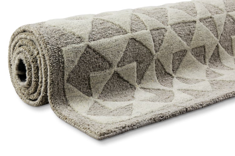 Zusammengerollter Hochflor-Teppich in Beige mit geometrischem Dreiecksmuster.