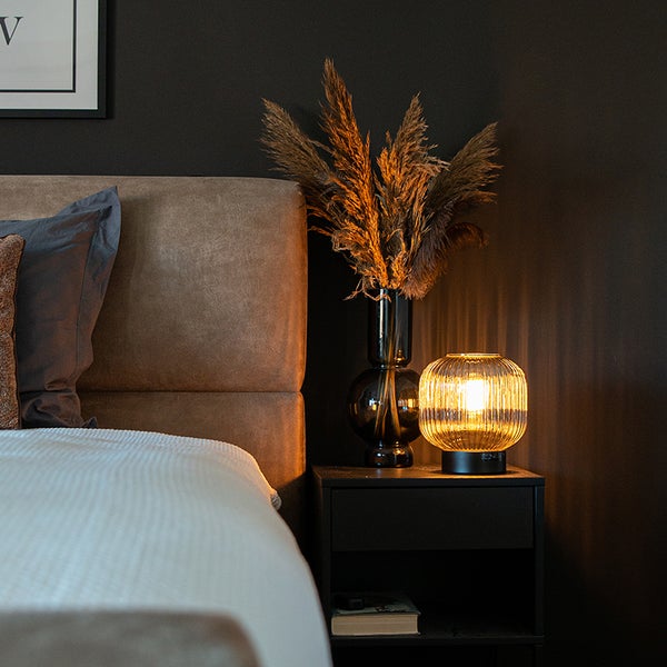 Schlafzimmer mit Bett, Nachttisch, Lampe und Dekoration