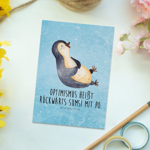 Ein Paar betrachtet eine Glückwunschkarte mit Pinguin Motiv.