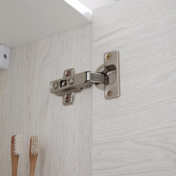 Nahaufnahme eines Metall-Scharniers montiert an einem Schrank mit Holzmaserung.
