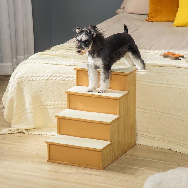 Hundetreppe aus Holz mit vier Stufen und hellem Teppichbelag vor einem Bett in einem hellen Schlafzimmer.