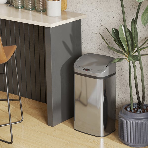 Silberfarbener, automatischer Abfalleimer neben einer Zimmerpflanze in einem Raum.