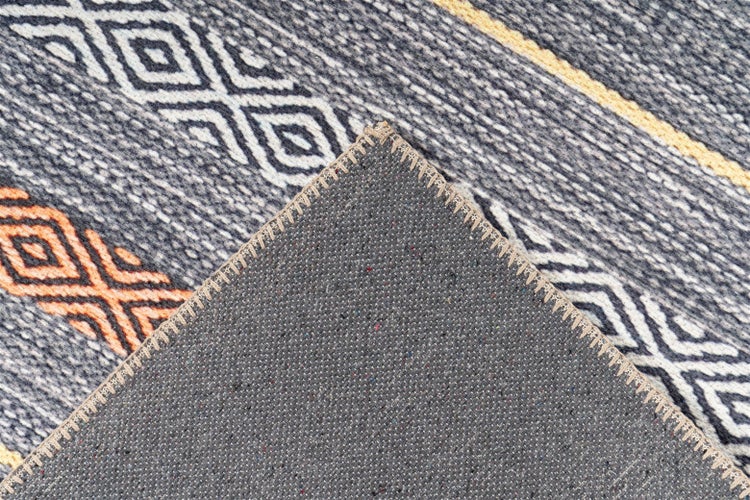 Detailaufnahme eines Teppichs mit geometrischem Muster und umgeklappter Ecke, die die strukturierte Rückseite und die Kettelung zeigt.