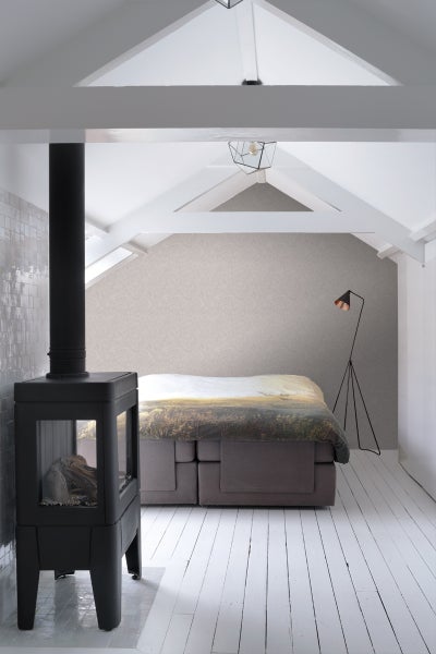 Ein Schlafzimmer mit einem Kaminofen, einem Bett und einer Stehlampe in einem Dachgeschoss.