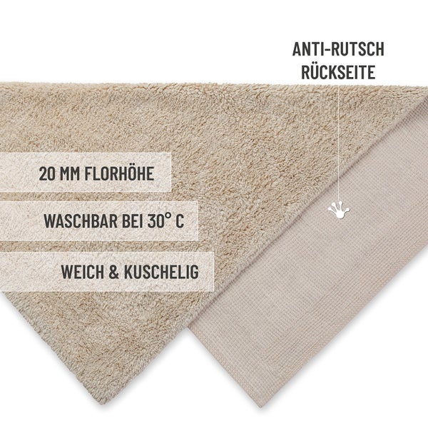 Runder, beigefarbener Badeteppich aus weichem Material auf einem Holzboden in einem hellen Badezimmer neben einer Badewanne und Holzregal.