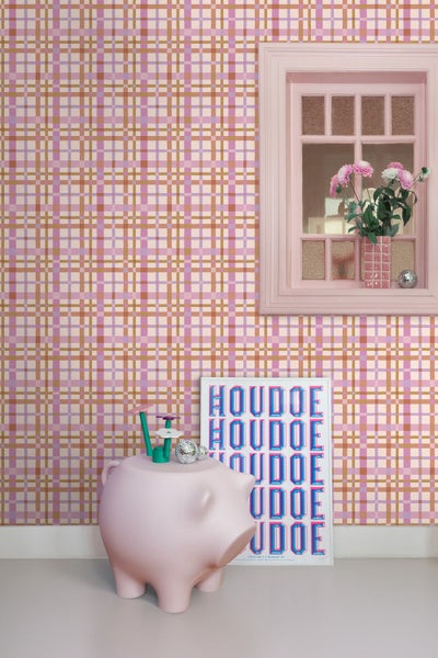 Vliestapete mit Karomuster in Rosa, Violett und Gold in einem hellen Zimmer mit dekorativem Schweine-Hocker.