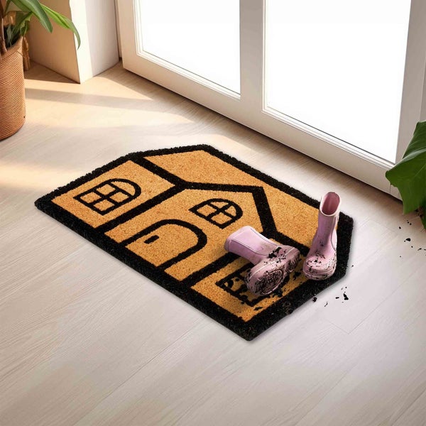 Fußmatte in Hausform mit Gummistiefeln vor einer Tür