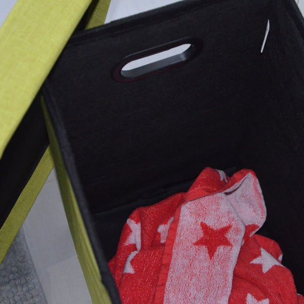 Aufbewahrungsbox aus Textil mit Grifföffnung und einem Handtuch im Inneren.
