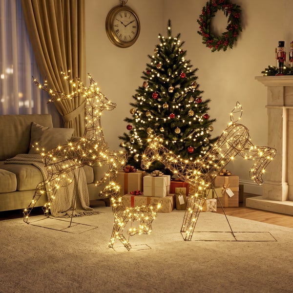 Drei beleuchtete Weihnachtsrentier-Figuren aus Drahtgeflecht mit LED-Lichtern als festliche Weihnachtsdekoration in einem Wohnzimmer.