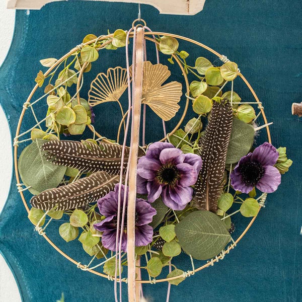 Dekorativer Ring mit Blättern, Federn und Blumen zur Wandgestaltung