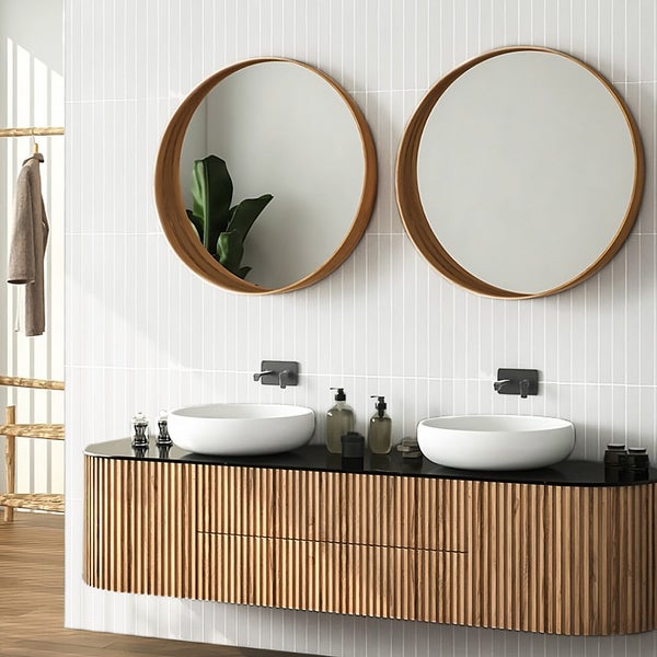 Modernes Badezimmer mit Doppelwaschtisch aus Holz, zwei runden Spiegeln und Aufsatzwaschbecken vor einer vertikal gefliesten Wand.