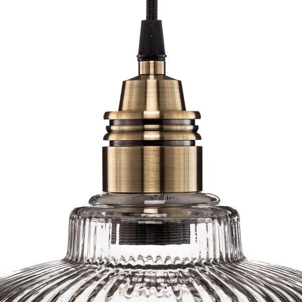 Nahaufnahme einer Pendelleuchte mit geriffeltem Glasschirm und einer Lampenfassung in Messingoptik.