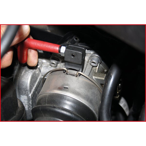 Detailaufnahme einer Hand, die einen roten T-Griff an einem Motor befestigt.