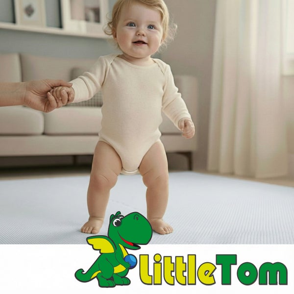 Kleinkind auf einer hellen Spielmatte aus Schaumstoff in einem hellen Wohnzimmer, gestützt von einer Hand. LittleTom Logo.