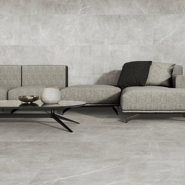 Wohnzimmer mit großformatigen Fliesen in Marmoroptik an Wand und Boden, modernes Sofa und Beistelltisch in einem hellen und geräumigen Ambiente.