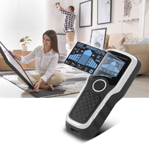 Digitales Ortungsgerät mit Stahlwerk Logo und Messanzeige. Im Hintergrund hängt ein Paar Bilder in einem hellen, organisierten Wohnzimmer auf.