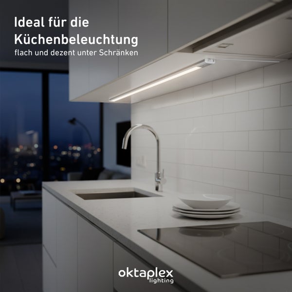 Küchenszene mit flacher Unterbauleuchte unter einem Hängeschrank, Spüle, Geschirr und Induktionskochfeld.