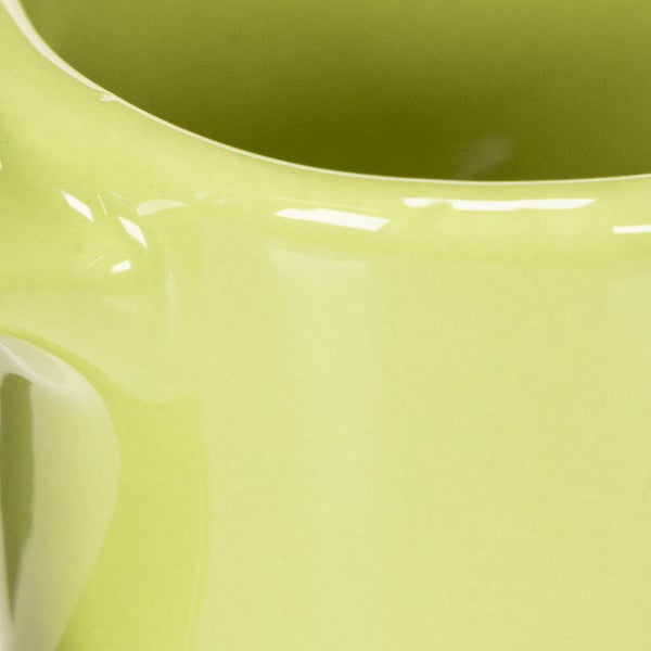 Nahaufnahme der Oberfläche eines glänzenden hellgrünen Blumentopfs aus Keramik mit abgerundetem Rand.