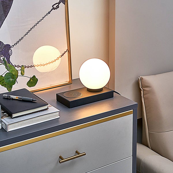 Tischleuchte mit kabelloser Ladestation auf einem Nachttisch