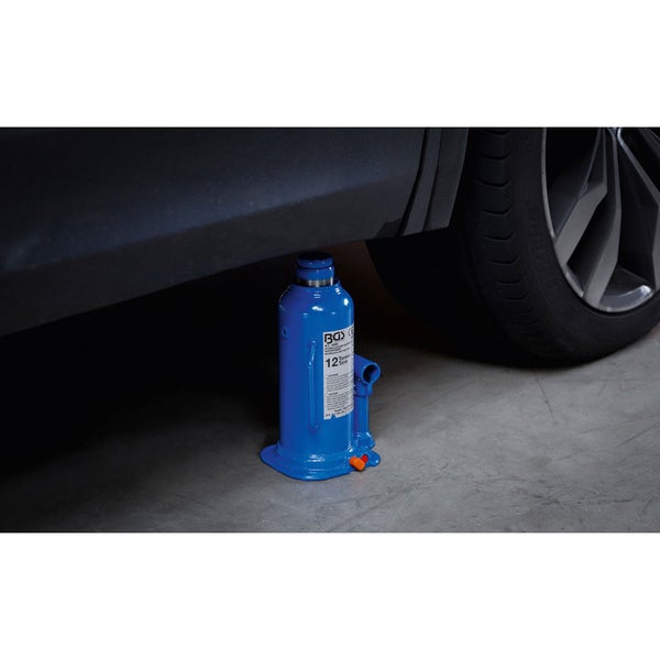 Hydraulischer Stempelwagenheber mit 12 Tonnen Tragkraft unter einem Fahrzeug neben einem Rad auf Betonboden.