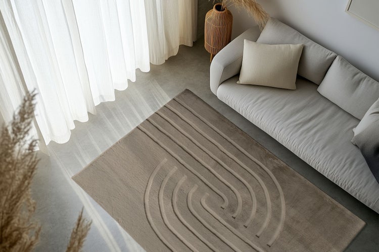 Wohnzimmer mit modernem Sofa und rechteckigem Teppich mit abstraktem, erhabenem Linienmuster in einem hellen und stilvoll eingerichteten Raum.