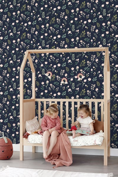 Kinderzimmer mit floral gemusterter Tapete, Holzbett und zwei spielenden Mädchen
