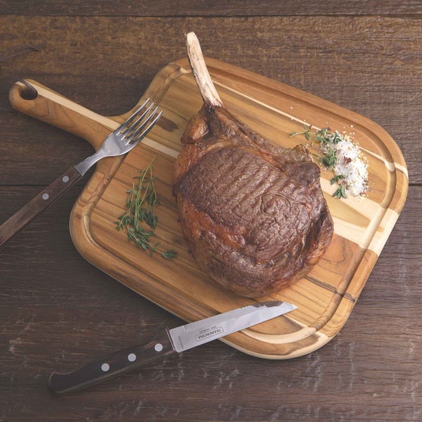 Tomahawk Steak auf Holzbrett mit Messer und Gabel