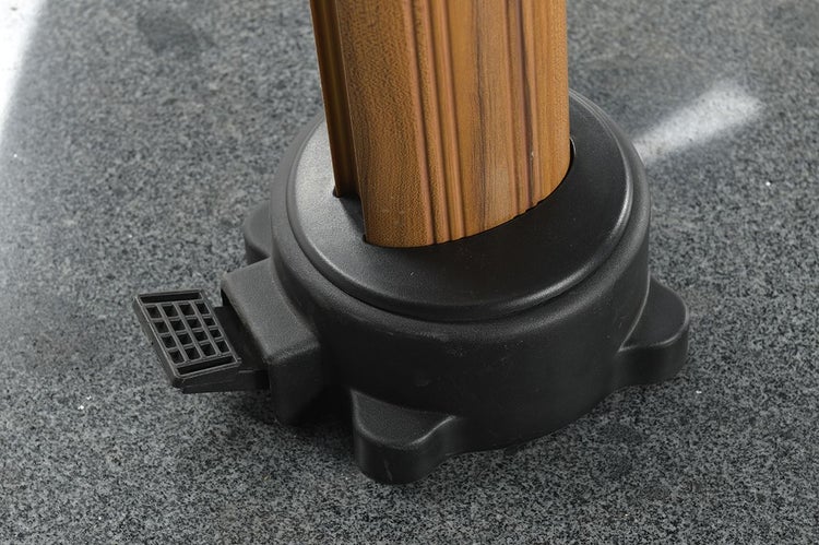 Nahaufnahme eines Sonnenschirmständers mit Fußpedal und Schirmmast in Holzoptik.