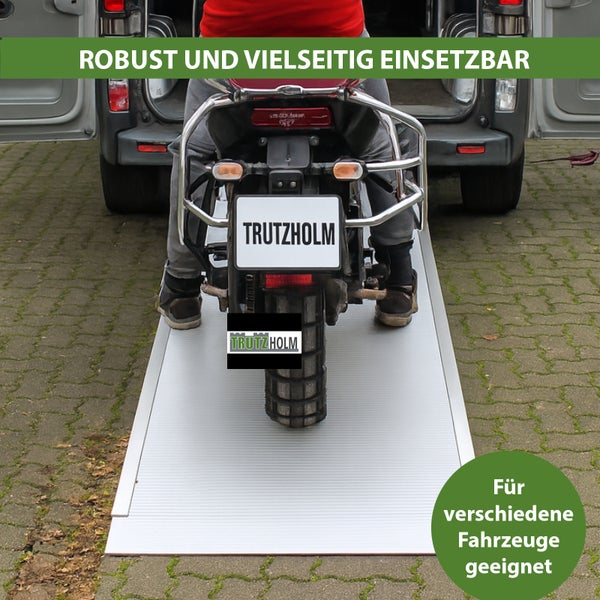 Motorrad auf einer Verladeschiene vor einem Transporter