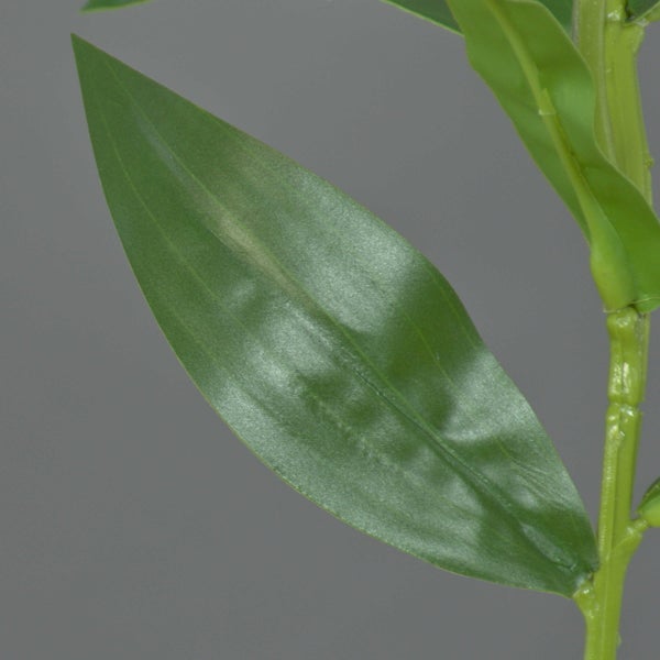 Nahaufnahme eines grünen Kunststoffblattes an einem Stiel einer Kunstpflanze.