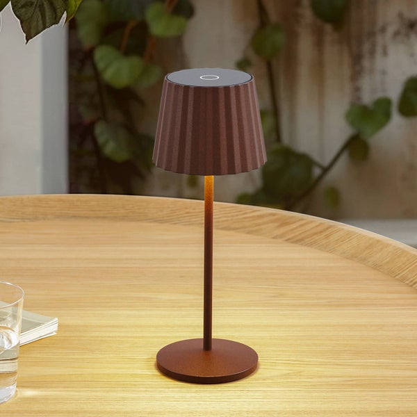 Mobile Tischleuchte mit geriffeltem Schirm auf einem Holztisch, warmes Licht nach unten gerichtet.