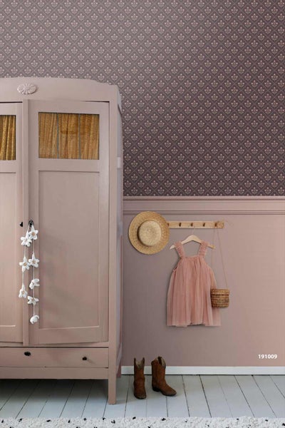 Eingerichteter Raum mit gemusterter Tapete, einem Kleiderschrank aus Holz und einer Hakenleiste mit Kleidung an einer gestrichenen Wand.