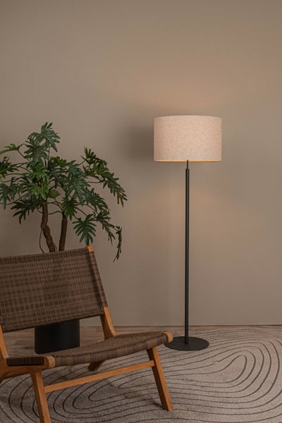 Eine Inneneinrichtung mit einem Sessel, einer Zimmerpflanze und einer Stehlampe.