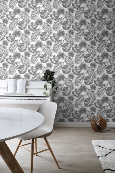 Ein heller Raum mit einem Klavier, einem Esstisch und einer Wand mit Blattmuster-Tapete.