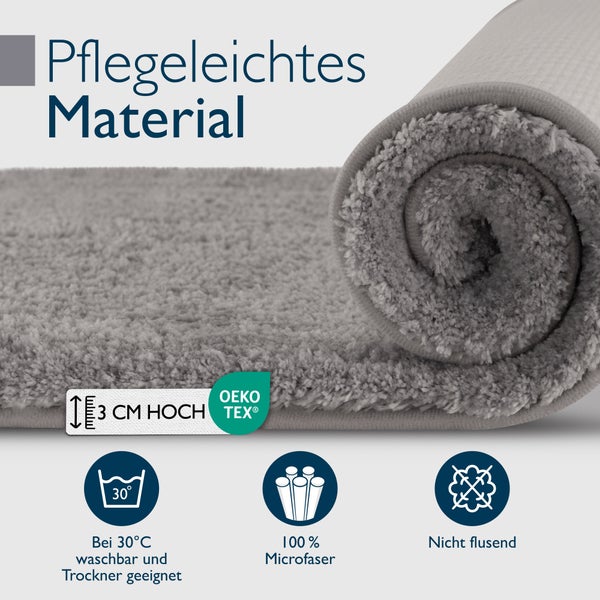 Graue Badematte gerollt mit Pflegehinweisen: waschbar bei 30 Grad, trocknergeeignet, aus Mikrofaser, fusselfrei, Höhe drei Zentimeter, Oeko-Tex Siegel