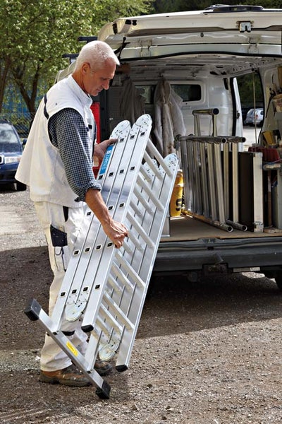 Handwerker mit Mehrzweckleiter vor Lieferwagen