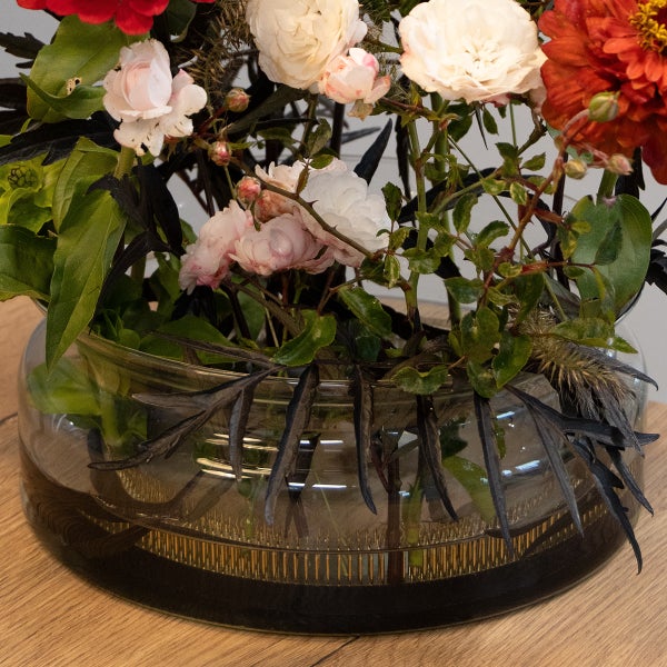 Blumensteckigel Kenzan in einer Glasschale mit einem hellen Blumenarrangement auf einer Holzoberfläche.