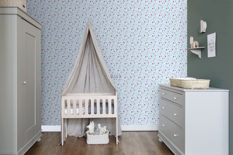 Hell eingerichtetes Kinderzimmer mit floraler Tapete, Babybett und Kommode