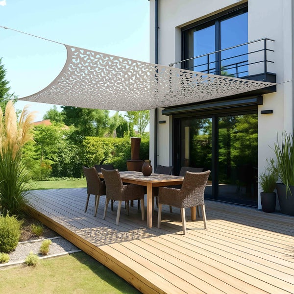 Sonnensegel mit lasergeschnittenem Muster über einer Holzterrasse mit Esstisch und Stühlen vor einem modernen Haus.