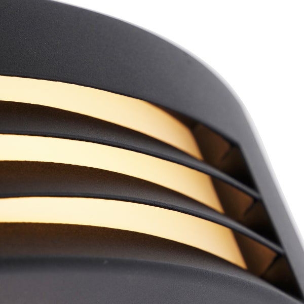 Detailaufnahme einer schwarzen Außenwandleuchte mit horizontalen Lamellen und goldfarbenem Innenraum.
