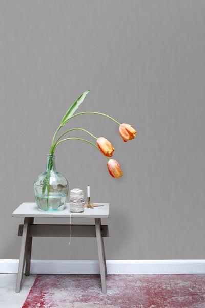 Dekorative Szene mit Tulpen in einer Vase auf einem Beistelltisch vor einer Wand