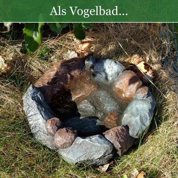 Vogelbad in Naturstein-Optik im Garten auf einer Rasenfläche.