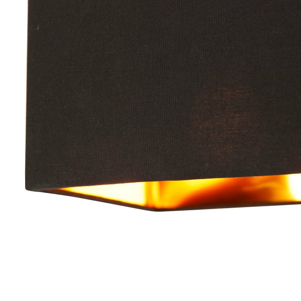 Detailansicht eines Lampenschirms aus Stoff mit goldfarbener Innenseite und warmem Lichtschein.