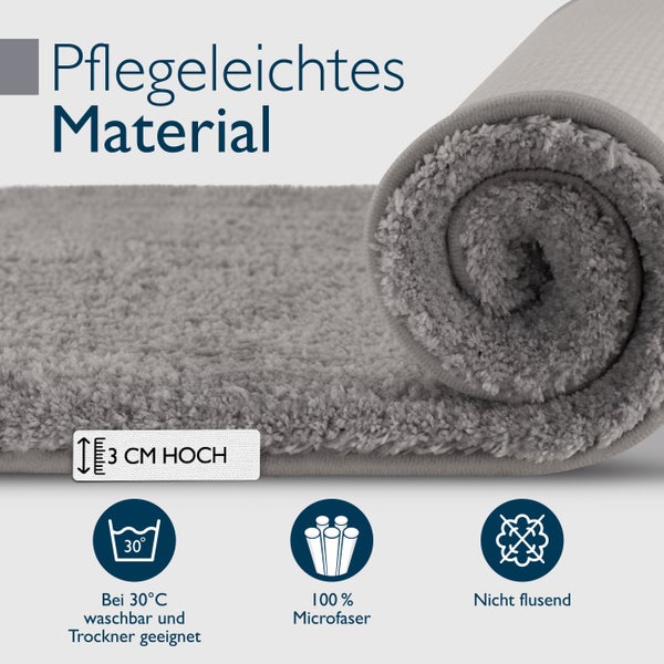 Ein aufgerollter Badezimmerteppich aus pflegeleichtem Mikrofasermaterial mit einer Florhöhe von 3 Zentimeter, waschbar bei 30 Grad und fusselfrei.