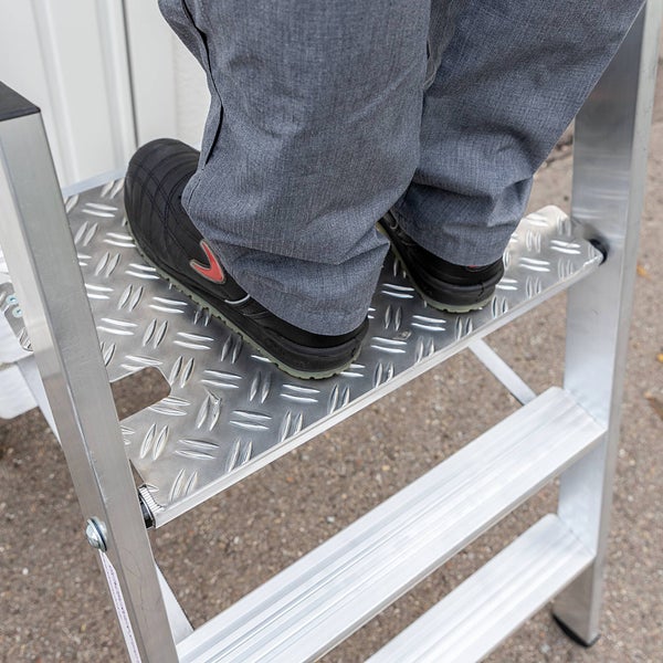 Person steht auf einer Aluminium Leiter